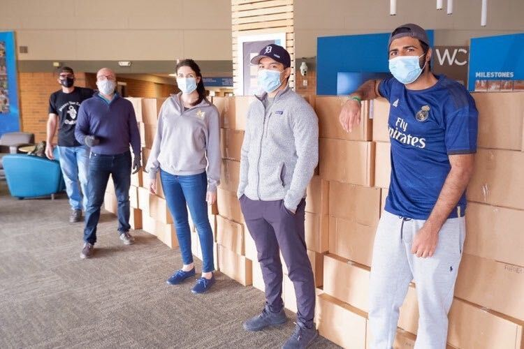 Masked people with boxes of PPE