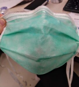 healthcare worker's reused mask demonstrates the PPE shortage