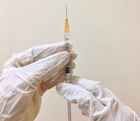 vaccine syringe held by gloved hands
