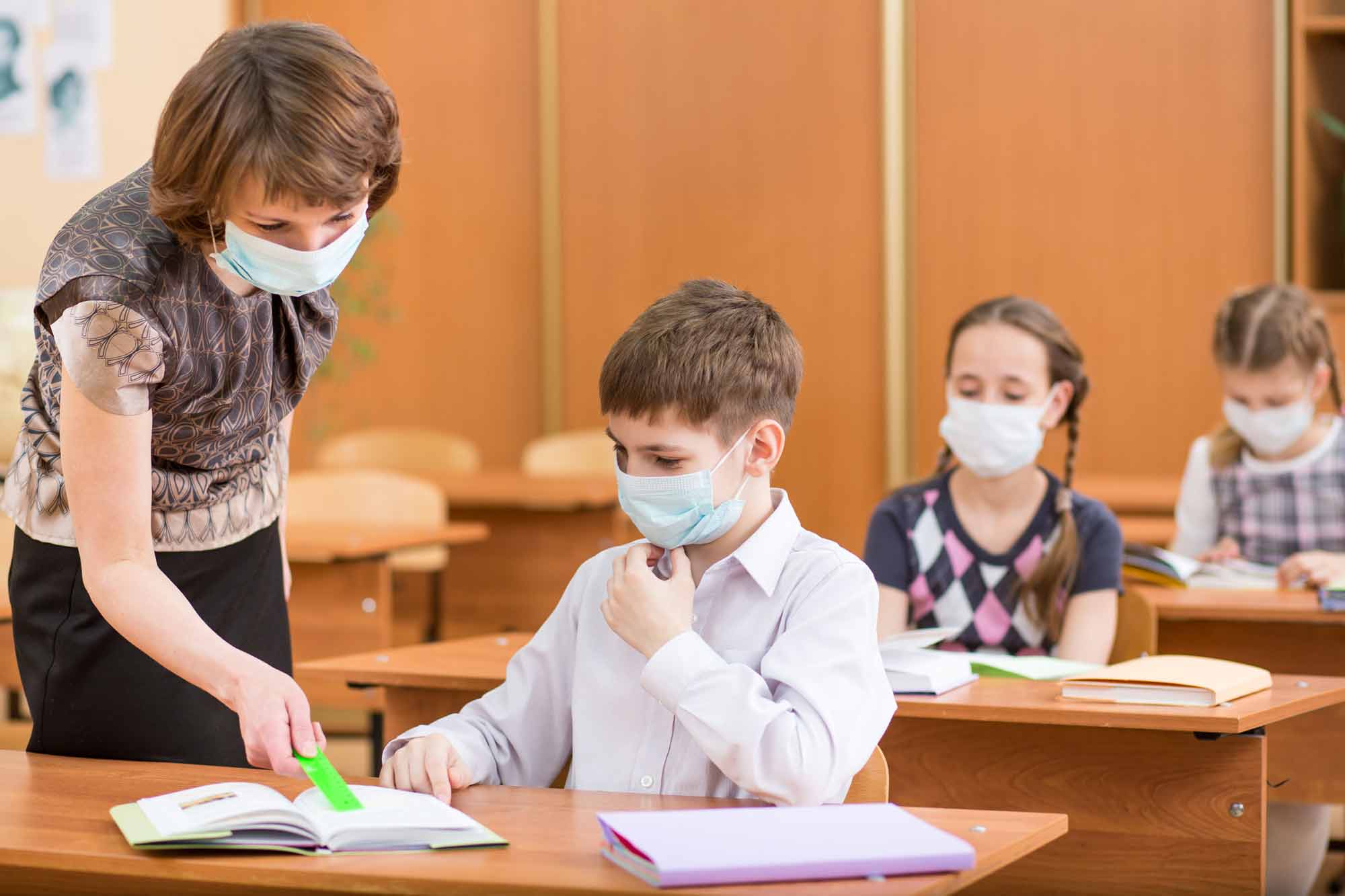 masked teacher and students in school classroom