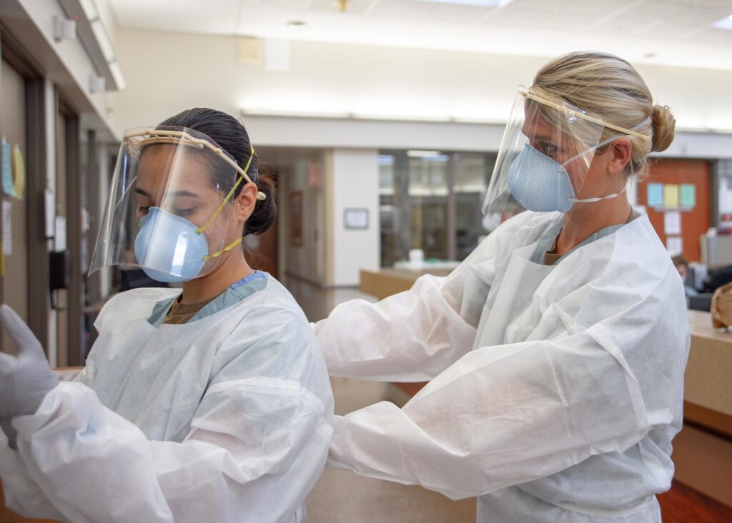 healthcare workers don PPE before visiting COVID-19 patient's room